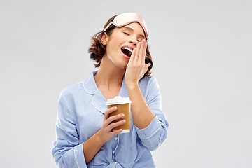 Image showing woman in pajama and eye mask with coffee yawning