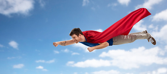 Image showing man in red superhero cape flying over sky