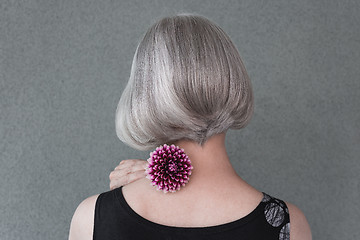 Image showing Lady with beautiful silver hair and red dahlia