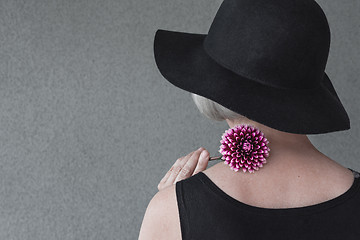 Image showing Lady with black hat holding red dahlia