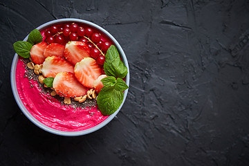 Image showing Summer berry smoothie or yogurt bowl with strawberries, red currants and chia seeds on black