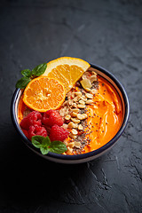 Image showing Bowl with fresh healthy smoothie or yogurt. With orange slices, tangerine, raspberry, chia and nuts