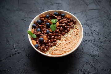 Image showing Chocolate and blueberry smoothie or yogurt. With cocoa cornflakes, granola, mint leaves and almonds