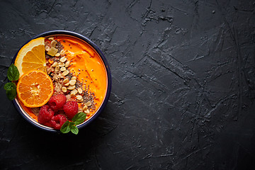 Image showing Bowl with fresh healthy smoothie or yogurt. With orange slices, tangerine, raspberry, chia and nuts