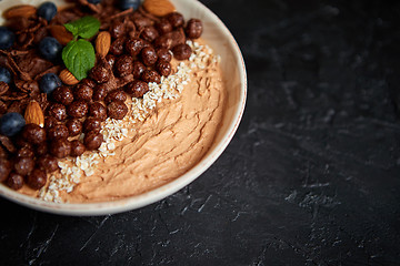 Image showing Chocolate and blueberry smoothie or yogurt. With cocoa cornflakes, granola, mint leaves and almonds