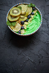 Image showing Green smoothie or yogurt bowl. With fresh kiwi, blueberries, lime and almond flakes