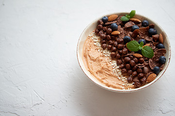 Image showing Chocolate and blueberry smoothie or yogurt. With cocoa cornflakes, granola, mint leaves and almonds