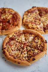 Image showing Three american style pizzas served on a table