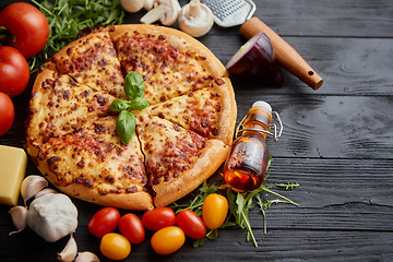 Image showing Fresh baked, hot american style pizza with all various ingredients on side