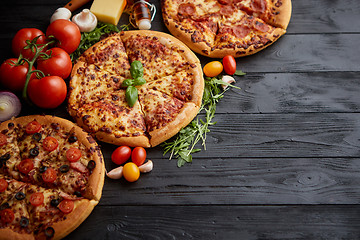 Image showing Freshly served, three various pizzas placed among tasty ingredie