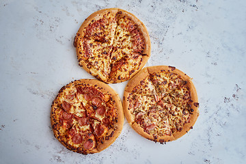 Image showing Three american style pizzas served on a table