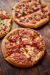 Image showing Composition of three various kinds pizzas on wooden table