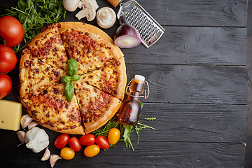 Image showing Fresh baked, hot american style pizza with all various ingredients on side