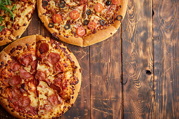 Image showing Composition of three various kinds pizzas on wooden table