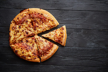 Image showing Fluffy pepperoni pizza in american style placed on rusty old black wooden table