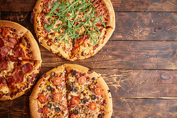 Image showing Composition of three various kinds pizzas on wooden table