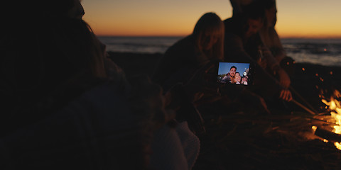 Image showing Couple taking photos beside campfire on beach