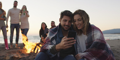 Image showing Couple enjoying bonfire with friends on beach