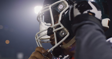 Image showing American Football Player Putting On Helmet on large stadium with