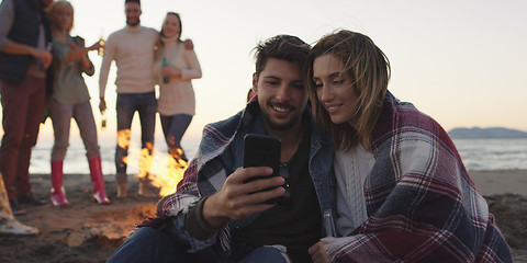 Image showing Couple enjoying bonfire with friends on beach