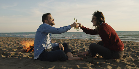 Image showing Loving Young Couple Sitting On The Beach beside Campfire drinkin