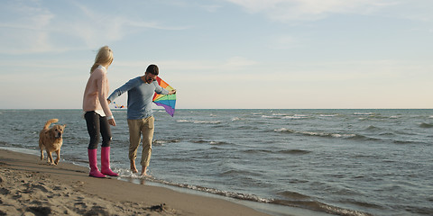 Image showing couple with dog having fun on beach on autmun day