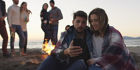 Image showing Couple enjoying bonfire with friends on beach