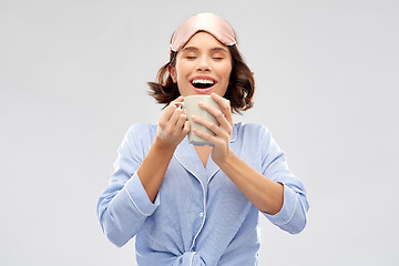 Image showing woman in pajama and sleeping mask drinking coffee