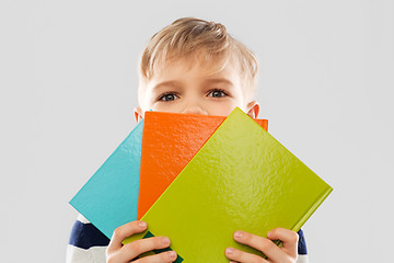 Image showing shy schoolboy hiding behind books