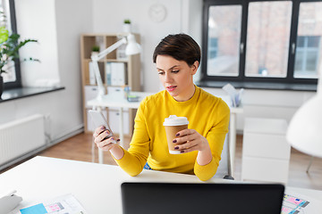 Image showing woman with coffee using smartphone at office