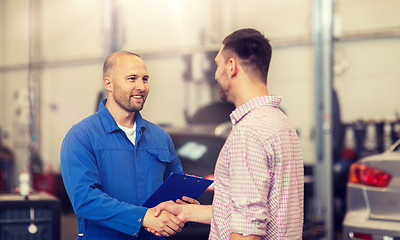 Image showing auto mechanic and man shaking hands at car shop