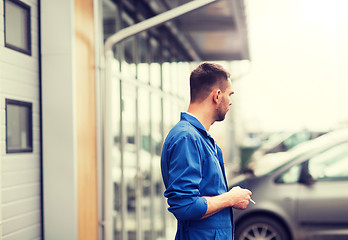 Image showing auto mechanic smoking cigarette at car workshop