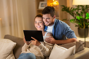 Image showing happy couple using tablet pc at home in evening