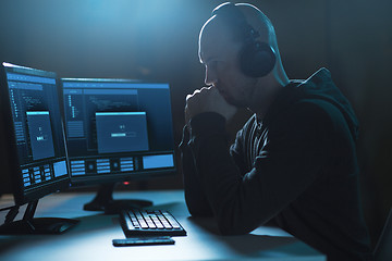 Image showing hacker with progress bar on computers in dark room