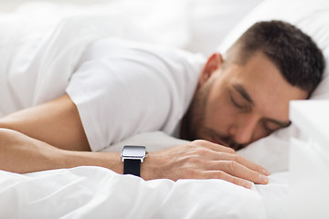 Image showing close up of man with smart watch sleeping in bed