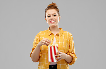 Image showing smiling red haired teenage girl eating popcorn