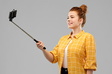 Image showing happy teenage girl taking picture by selfie stick