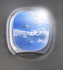 Image showing Shoal of fish in a cloudy blue sky through airplane porthole.