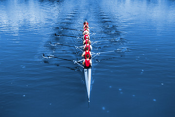 Image showing Boat coxed eight Rowers rowing on the blue lake. Classic Blue Pa