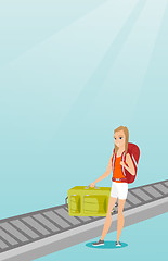 Image showing Woman picking up suitcase from conveyor belt.