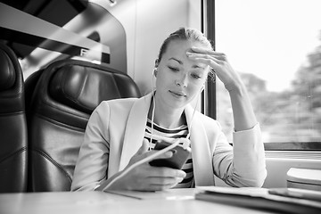 Image showing Businesswoman communicating on mobile phone while traveling by train.