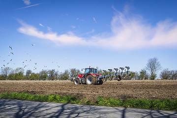 Image showing Red tractor ploughing a rural field in the spring