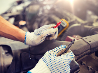 Image showing auto mechanic man with multimeter testing battery