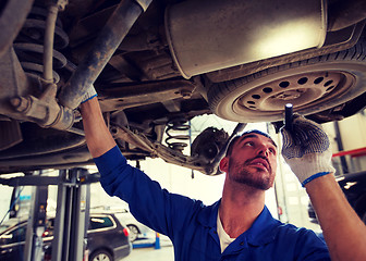 Image showing mechanic man with flashlight repairing car at shop