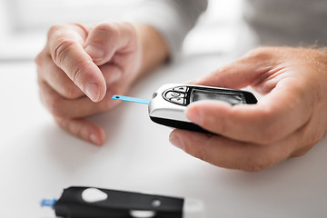 Image showing senior man with glucometer checking blood sugar