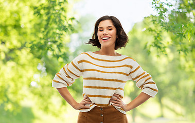 Image showing smiling woman in pullover with hands on hips