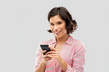 Image showing young woman in striped shirt using smartphone