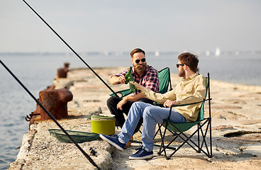 Image showing happy friends fishing and drinking beer on pier