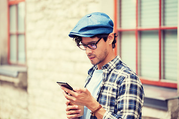 Image showing man with smartphone drinking coffee on city street