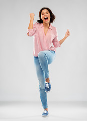 Image showing young woman in shirt and jeans celebrating success